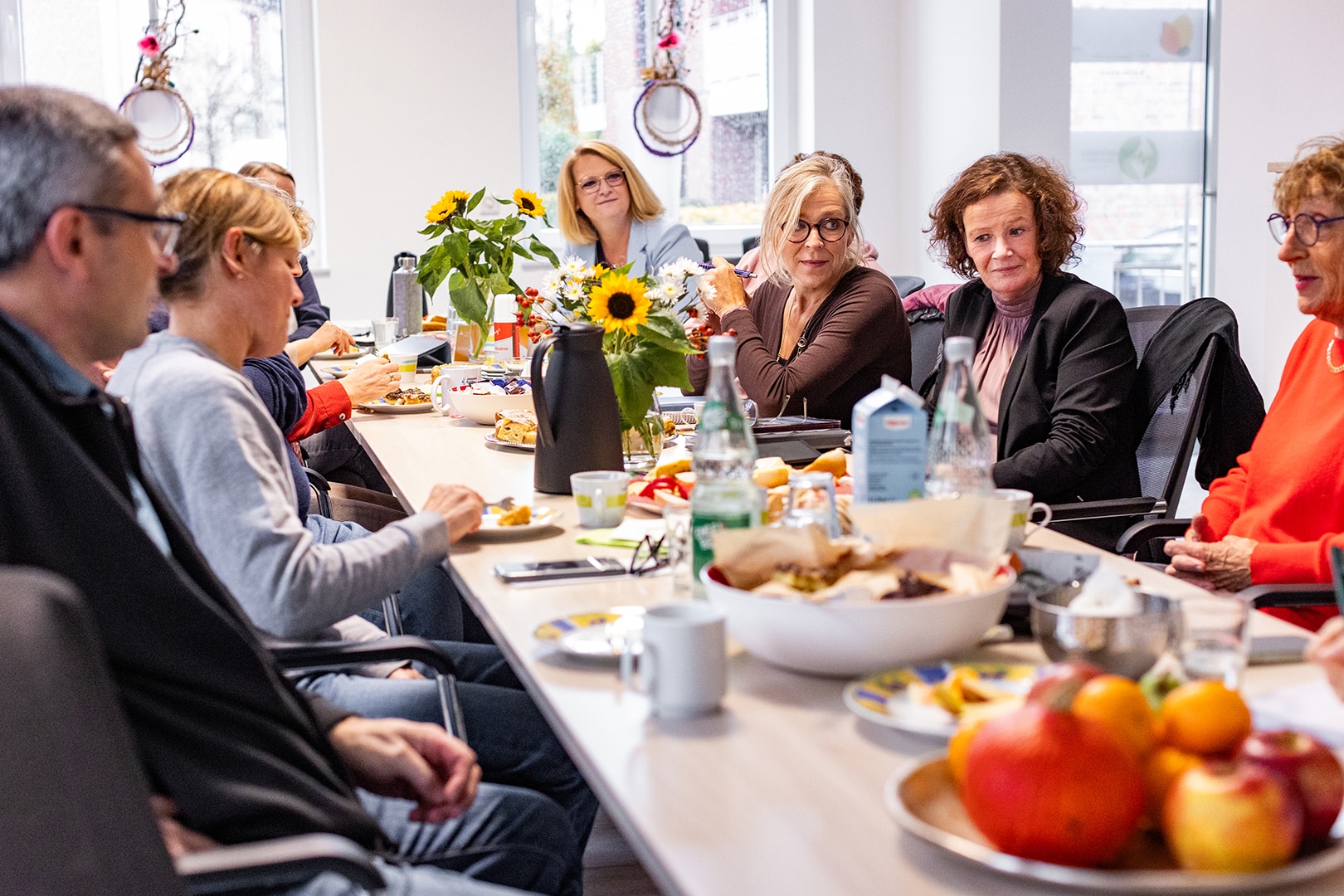 Einfühlsames Teamgespräch des Palliativdienstes im Kreis Coesfeld an einem Tisch mit Blumen und Snacks